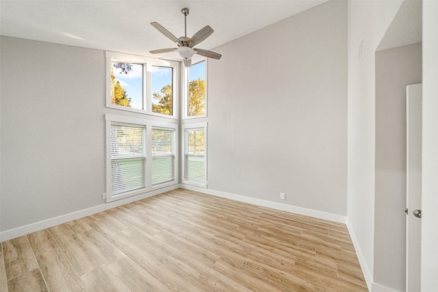 spare room featuring a high ceiling, light hardwood / wood-style floors, and ceiling fan