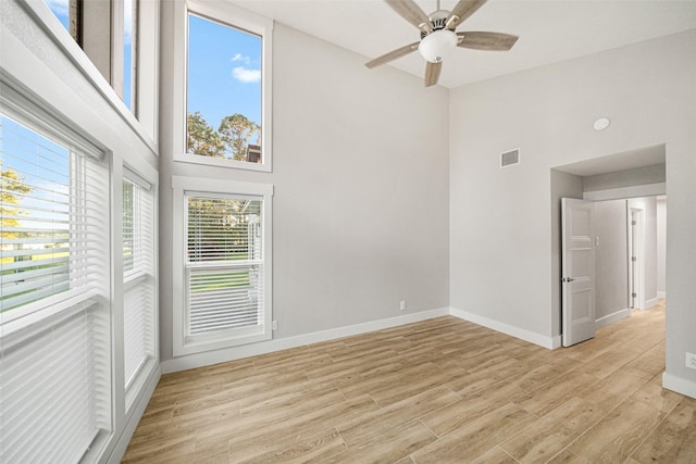 unfurnished room featuring ceiling fan, a high ceiling, and light wood-type flooring