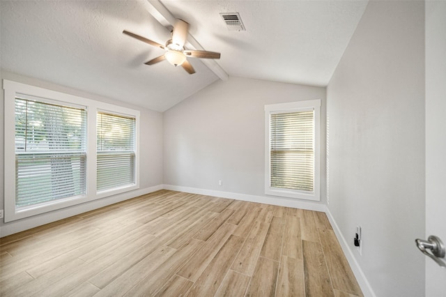 empty room featuring vaulted ceiling with beams, light hardwood / wood-style flooring, a wealth of natural light, and ceiling fan