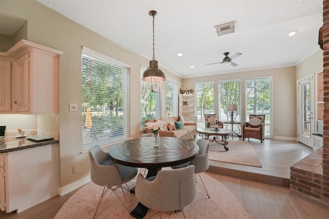 dining room featuring ceiling fan, crown molding, light hardwood / wood-style floors, and a textured ceiling