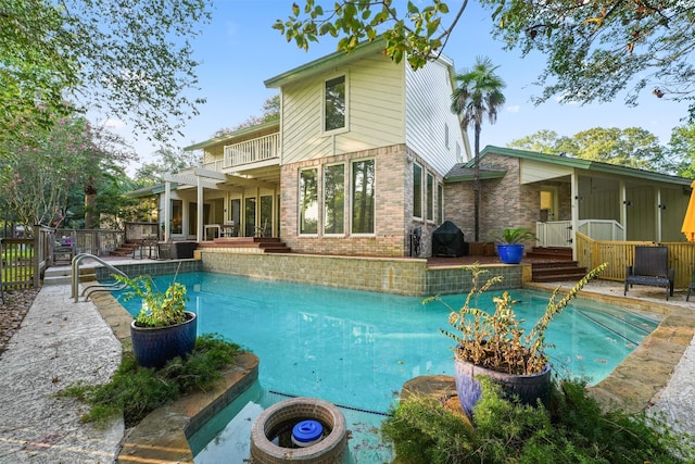 back of property featuring a fenced in pool and a balcony