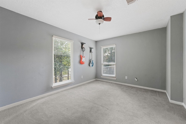 spare room featuring ceiling fan, light colored carpet, and a textured ceiling