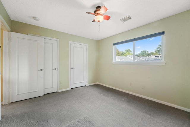 unfurnished bedroom with multiple closets, ceiling fan, and carpet