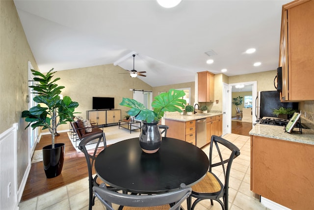 dining space featuring vaulted ceiling, light hardwood / wood-style flooring, ceiling fan, and sink