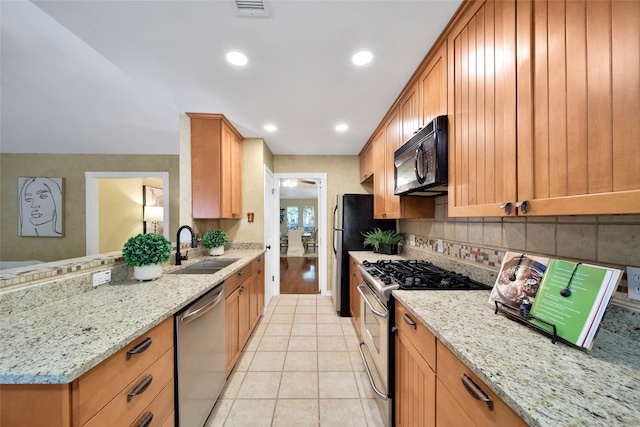 kitchen featuring light stone counters, sink, light tile patterned floors, and stainless steel appliances