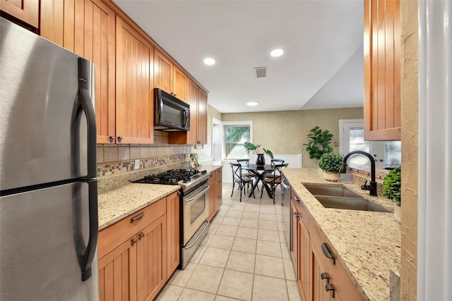 kitchen featuring light stone countertops, sink, stainless steel appliances, tasteful backsplash, and light tile patterned flooring