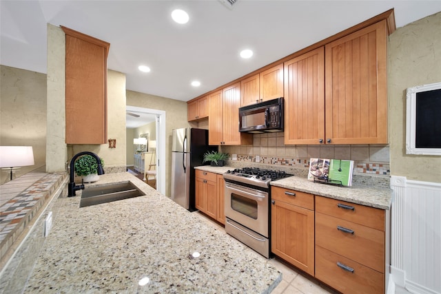 kitchen featuring backsplash, light stone counters, sink, and stainless steel appliances