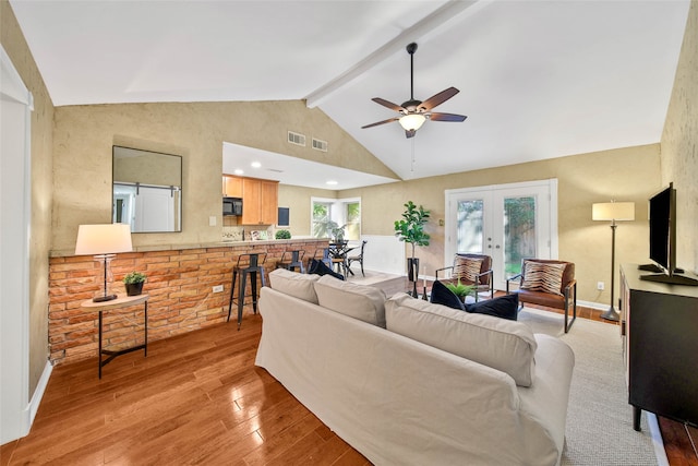 living room featuring lofted ceiling with beams, ceiling fan, light wood-type flooring, and french doors