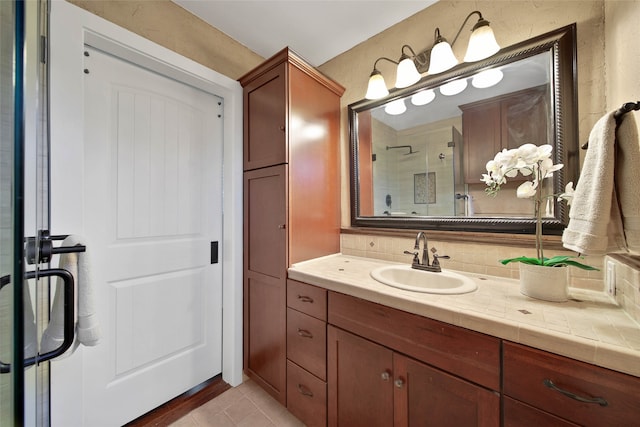 bathroom featuring tile patterned floors, vanity, a shower with door, and tasteful backsplash