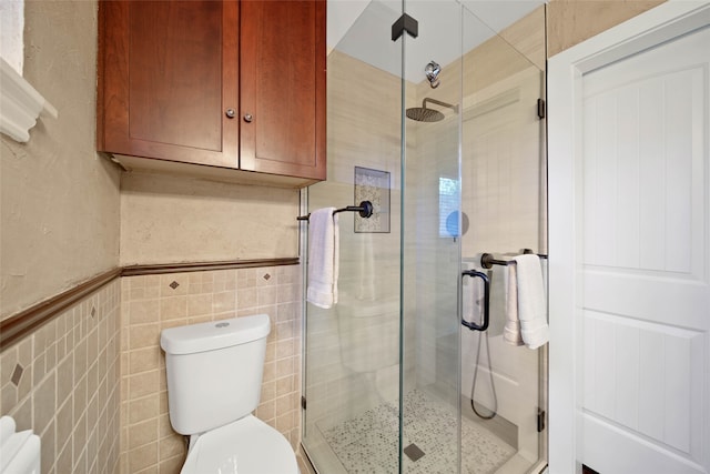 bathroom with an enclosed shower, tile walls, and toilet