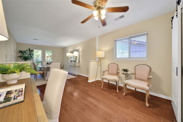 sitting room with a barn door, ceiling fan, and hardwood / wood-style flooring