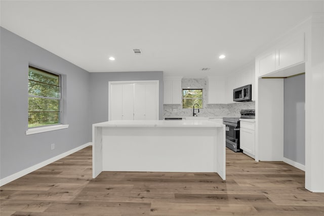 kitchen with stainless steel appliances, a kitchen island, and a wealth of natural light