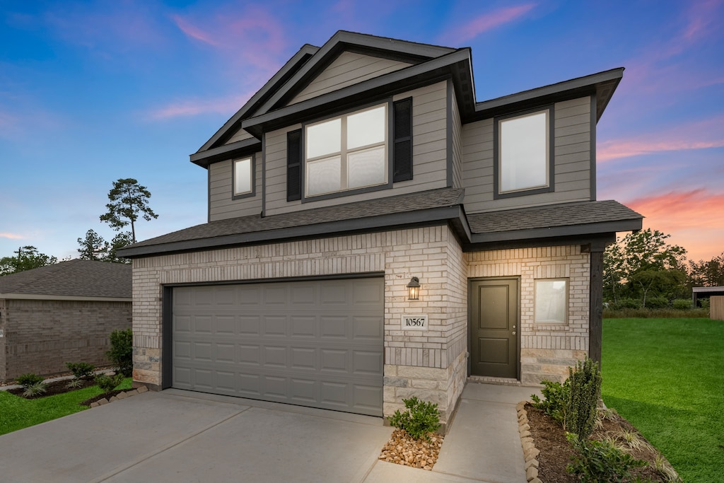 view of front of property with a garage and a lawn