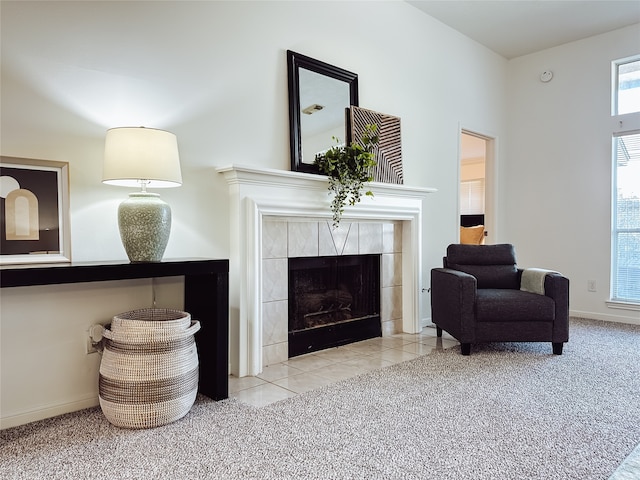 living area with light carpet and a tiled fireplace