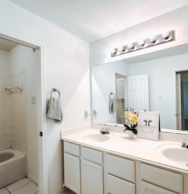 bathroom with tile patterned flooring, vanity, tiled shower / bath combo, and a textured ceiling