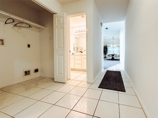 laundry area featuring electric dryer hookup, hookup for a washing machine, light tile patterned floors, and a chandelier