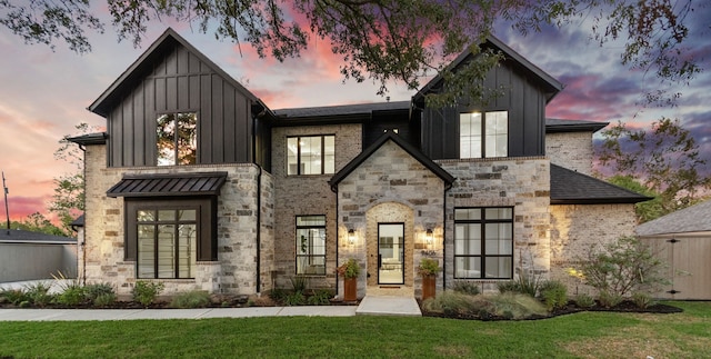 view of front facade featuring a standing seam roof, a front lawn, and board and batten siding