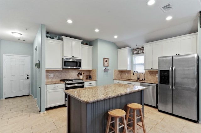 kitchen featuring appliances with stainless steel finishes, white cabinetry, a kitchen island, and sink