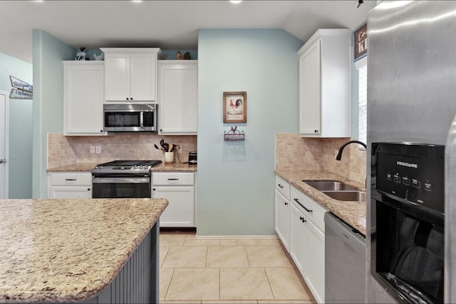 kitchen with light stone countertops, appliances with stainless steel finishes, tasteful backsplash, sink, and white cabinets