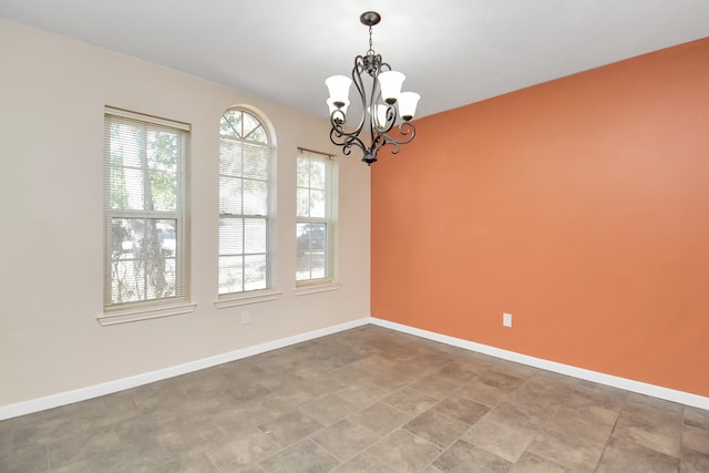 unfurnished room with a notable chandelier