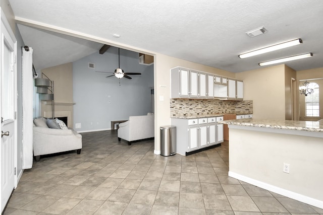 kitchen featuring light stone countertops, ceiling fan, vaulted ceiling with beams, light tile patterned flooring, and white cabinets