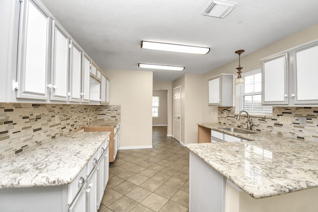 kitchen with pendant lighting, tasteful backsplash, white cabinetry, and sink