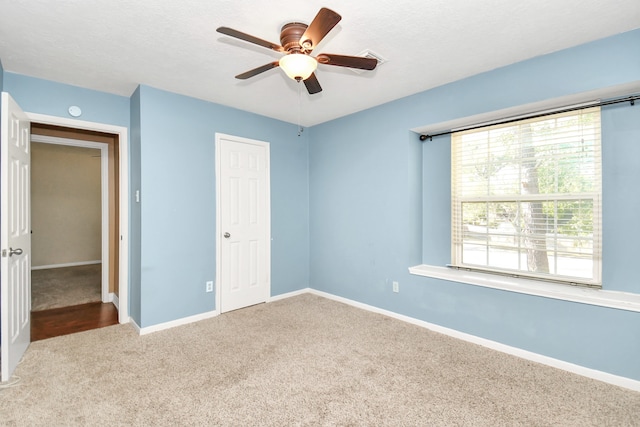 unfurnished bedroom with carpet flooring, ceiling fan, a closet, and a textured ceiling