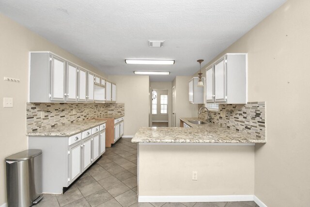 kitchen with kitchen peninsula, sink, white cabinets, and hanging light fixtures