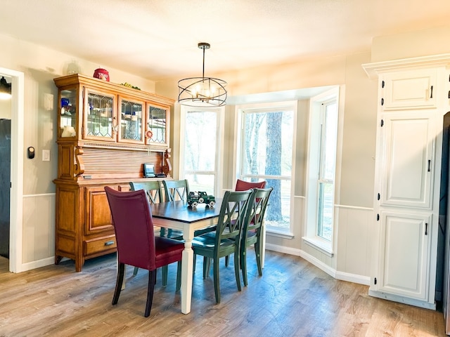 dining space with light wood-type flooring and an inviting chandelier