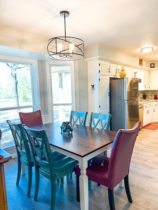 dining room with light wood-type flooring and a notable chandelier