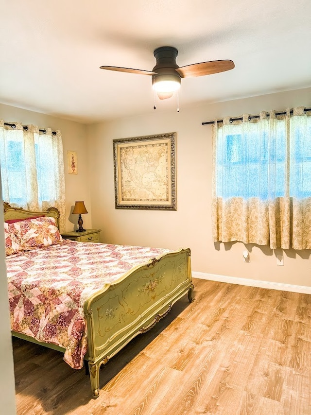 bedroom with ceiling fan, wood-type flooring, and multiple windows