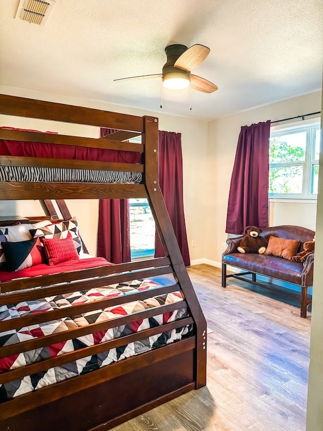 bedroom with ceiling fan, light hardwood / wood-style floors, and a textured ceiling