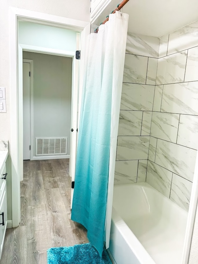 bathroom featuring hardwood / wood-style floors, vanity, and shower / bath combo with shower curtain