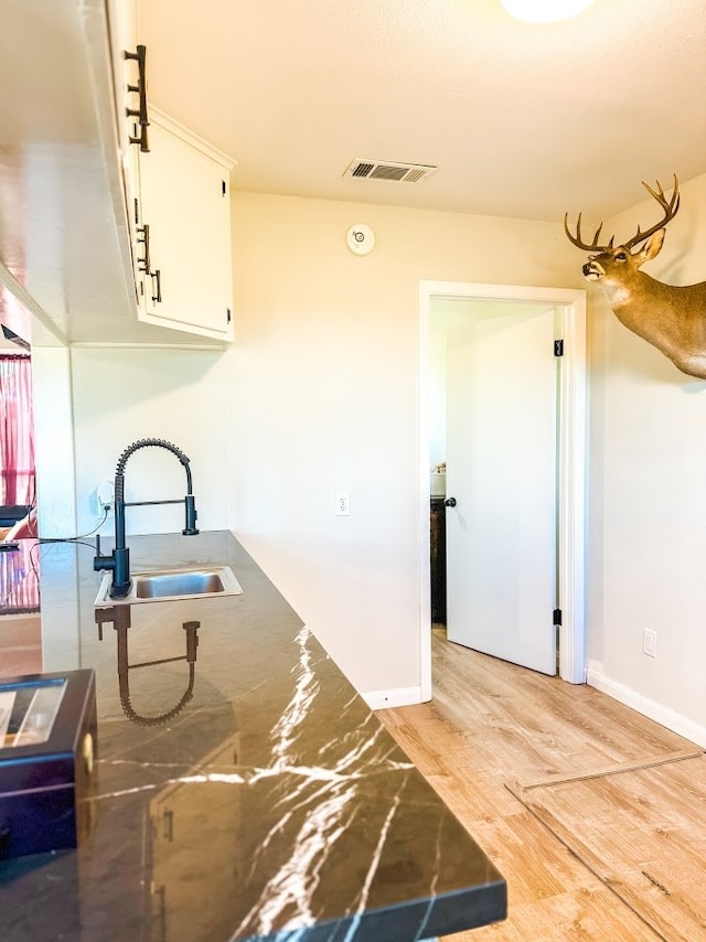 kitchen with white cabinets, light hardwood / wood-style flooring, and sink