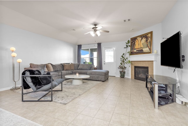 living room featuring a tiled fireplace, ceiling fan, and light tile patterned floors