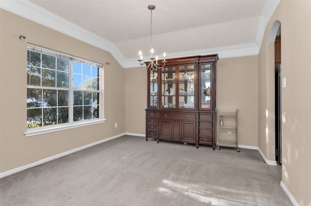 unfurnished dining area with carpet flooring, lofted ceiling, an inviting chandelier, and ornamental molding