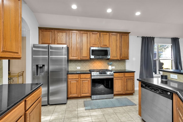 kitchen with tasteful backsplash, light tile patterned floors, and stainless steel appliances