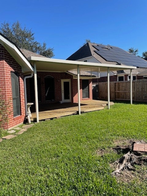 rear view of house featuring solar panels, a yard, and a deck