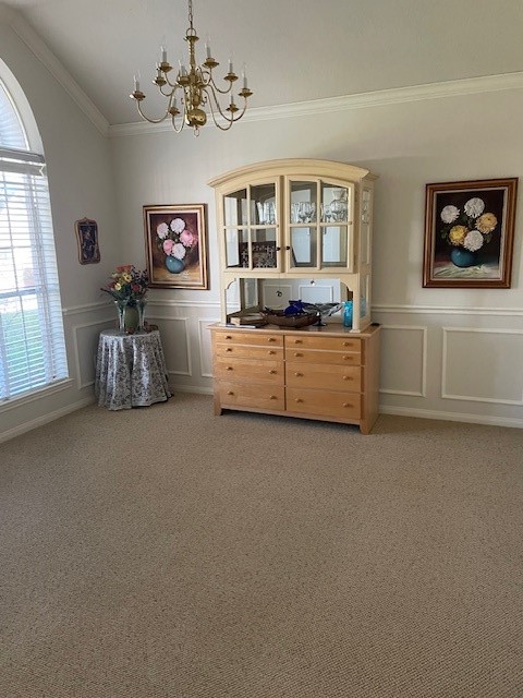 interior space featuring carpet, a chandelier, lofted ceiling, and ornamental molding