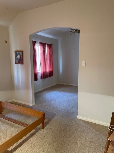 carpeted empty room with ceiling fan and lofted ceiling