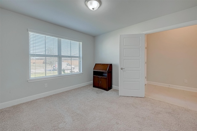 spare room featuring lofted ceiling and light colored carpet