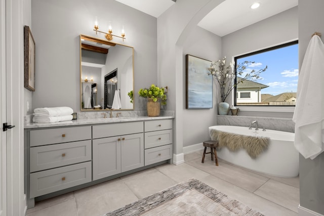 bathroom featuring tile patterned flooring, vanity, and a tub to relax in