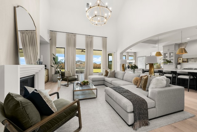 living room featuring a chandelier, a high ceiling, and light hardwood / wood-style flooring