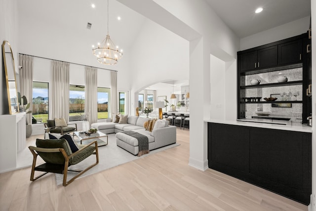 living room with a chandelier, light hardwood / wood-style floors, and high vaulted ceiling