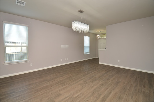 unfurnished room with dark hardwood / wood-style flooring and a notable chandelier