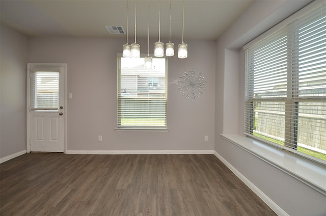 unfurnished dining area featuring a notable chandelier and dark hardwood / wood-style floors