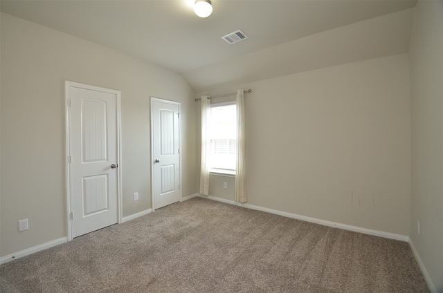 carpeted empty room with lofted ceiling