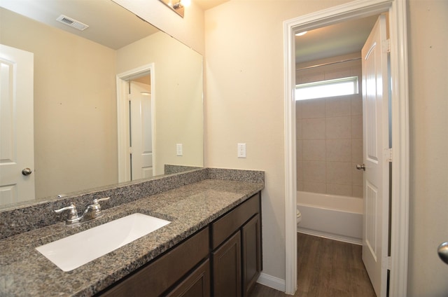 full bathroom with vanity, toilet, wood-type flooring, and tiled shower / bath combo