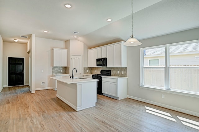 kitchen with white cabinetry, hanging light fixtures, black appliances, and vaulted ceiling