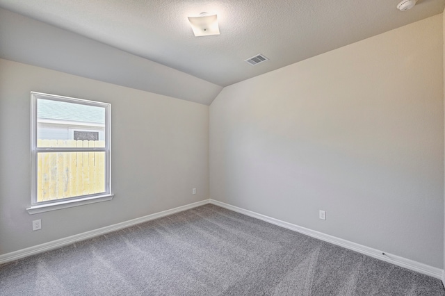 spare room featuring carpet flooring, a textured ceiling, and vaulted ceiling